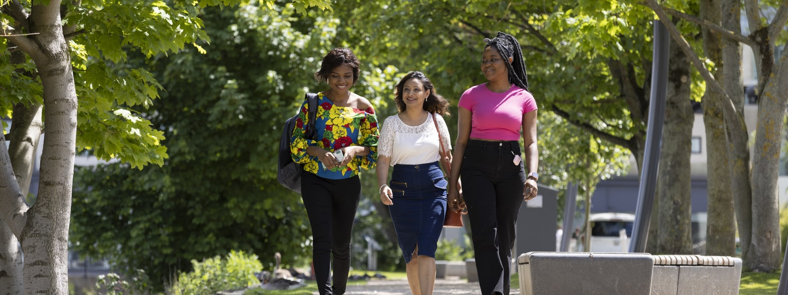 Three students walking on campus in summer