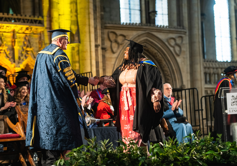 a student walking across the stage at graduation shaking the VC's hand