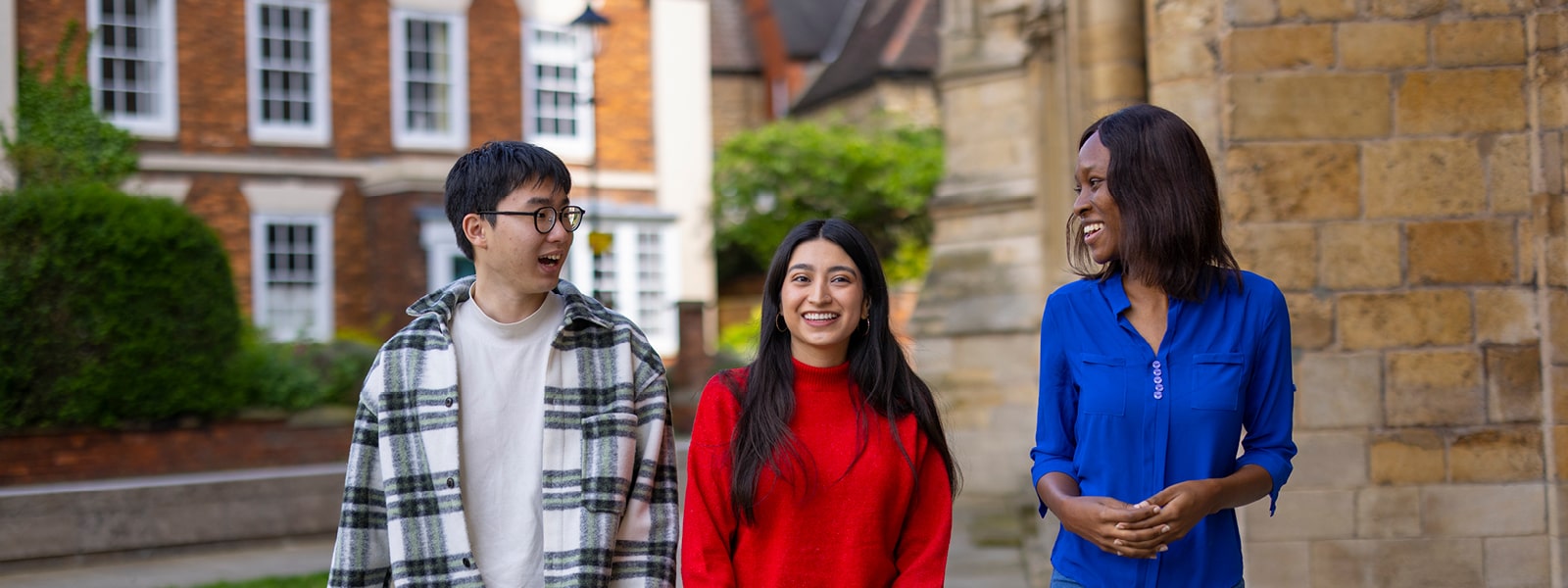 Three students smiling at each and the camera